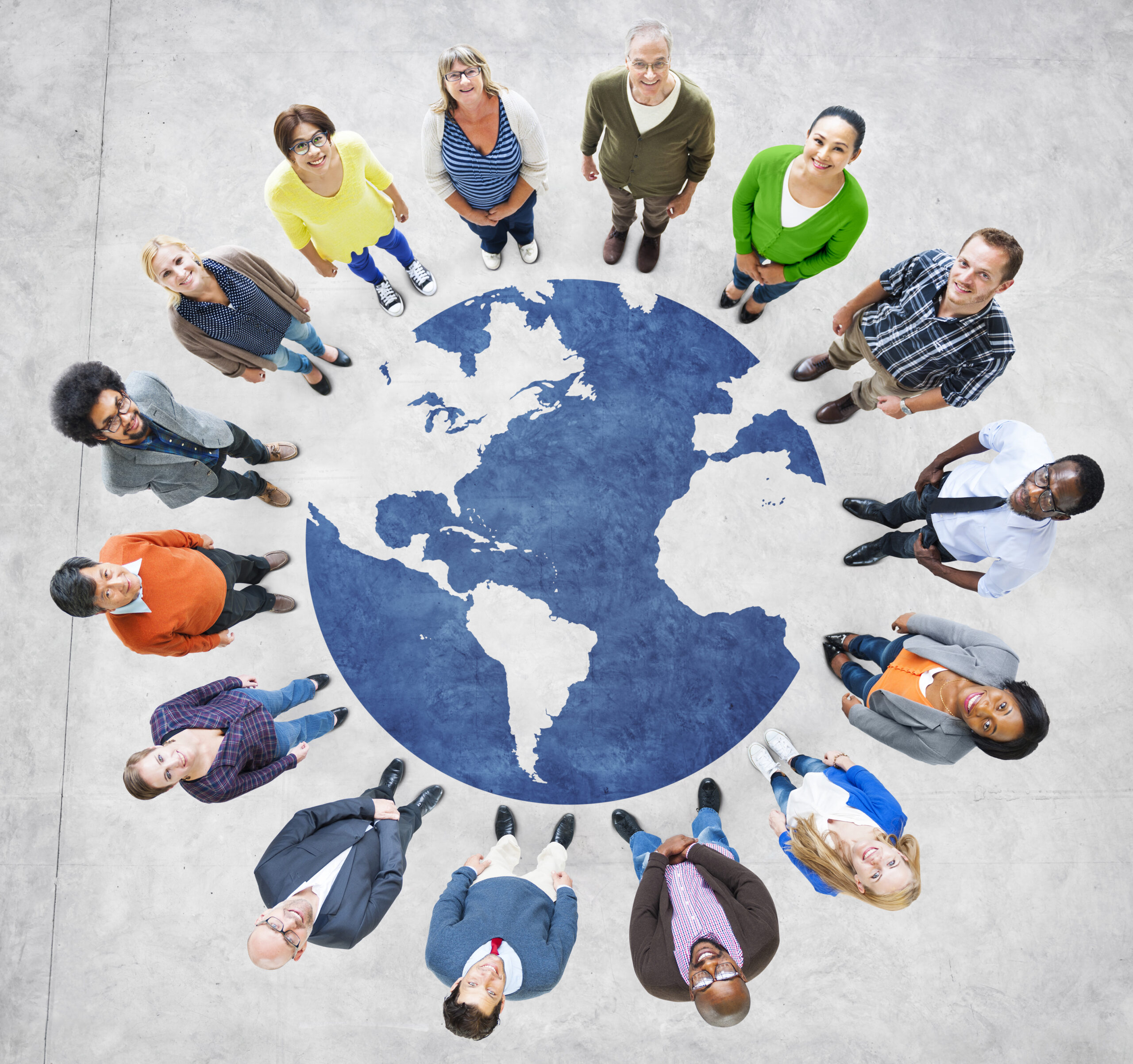 Diverse group of people standing around a large world map on the floor, symbolizing global unity and collaboration.